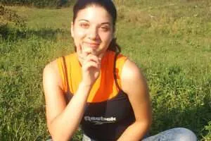 Woman sitting in field smiling at camera