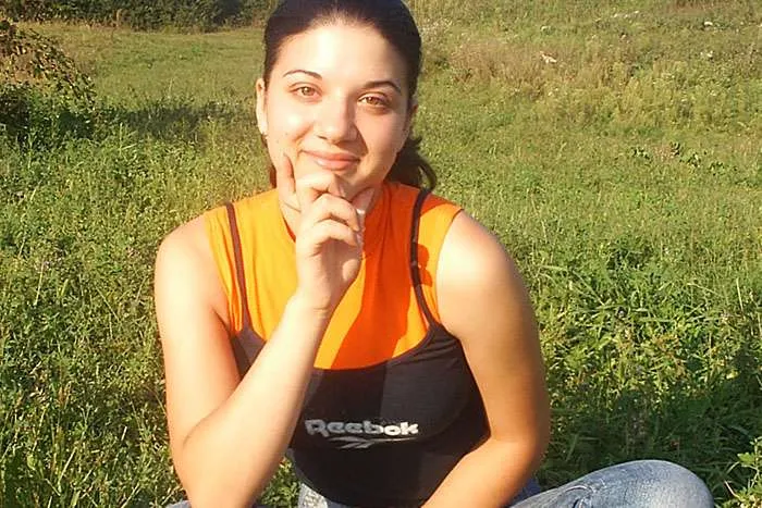 Woman sitting in field smiling at camera