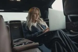 Woman sitting in back seat of car with laptop open on lap