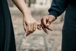 The hands of a man and woman with fingers intertwined