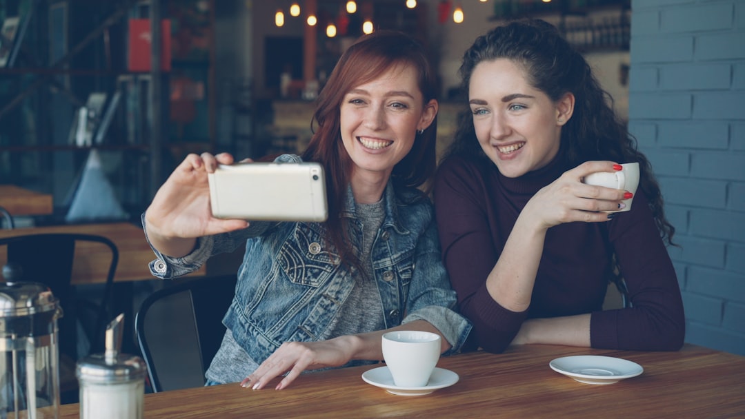 Two friends take a selfie in a cafe.