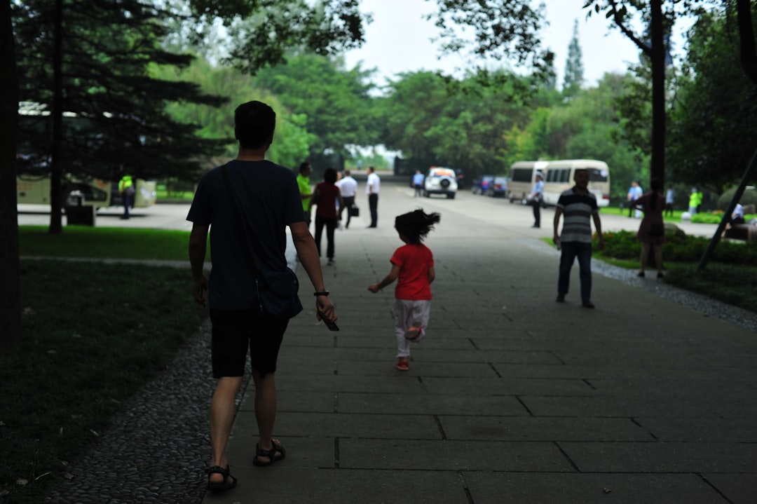 Man and child walking on park path with others.