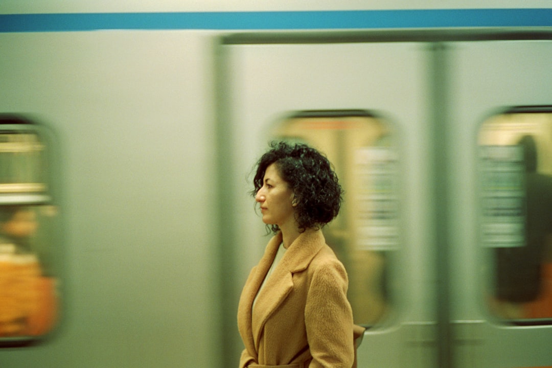 a woman in a tan coat is waiting for a train